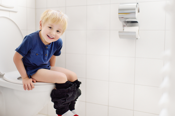 Boy sitting on toilet with pants down