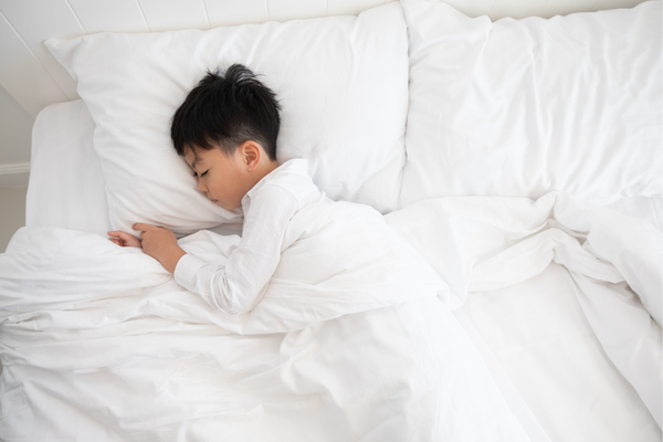 Boy sleeping on a white pillow with white bedsheets