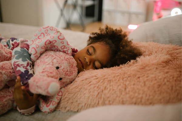 Little girl sleeping whilst holding a pink elephant toy