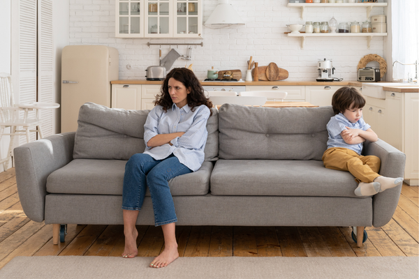 Frustrated mom and son crossing their arms whilst sitting on a couch
