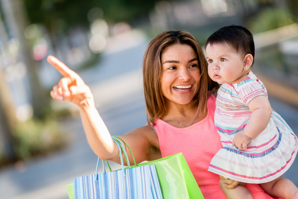 Mom holding baby pointing whilst carrying shopping bags