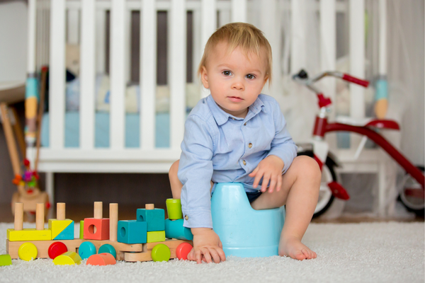 Toddler sitting on a blue potty with blocks