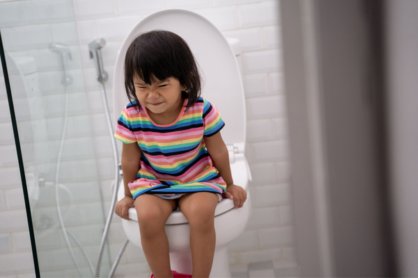 Girl sitting on a toilet trying to poop