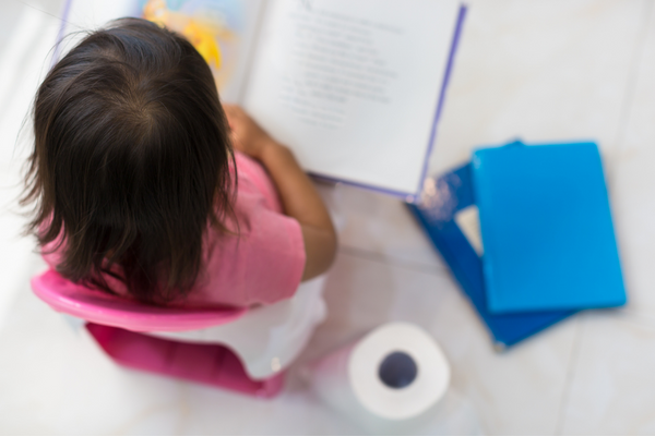 Girl sitting on a potty reading a book