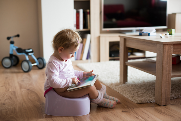 Girl sitting on a potty reading a book