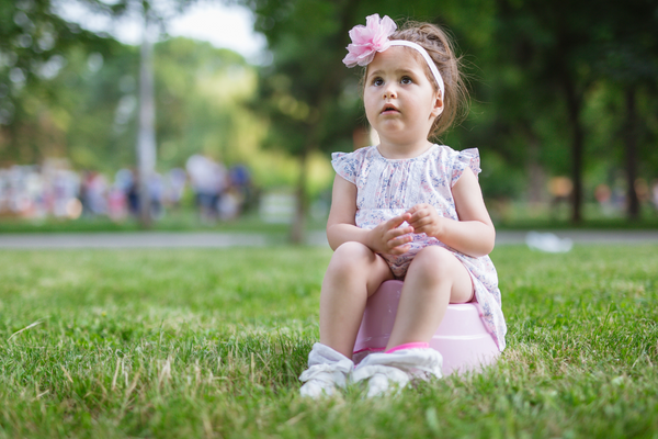 Girl sitting on a potty outside on grass