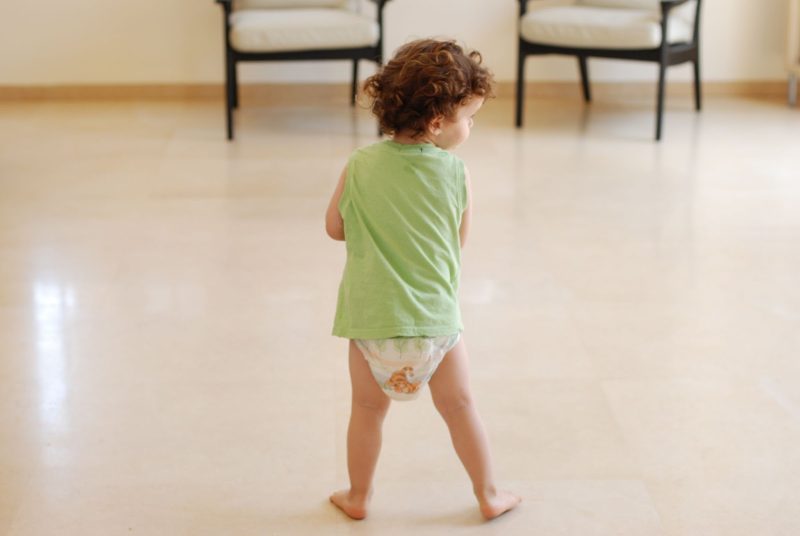Little boy wearing a diaper and a green singlet.